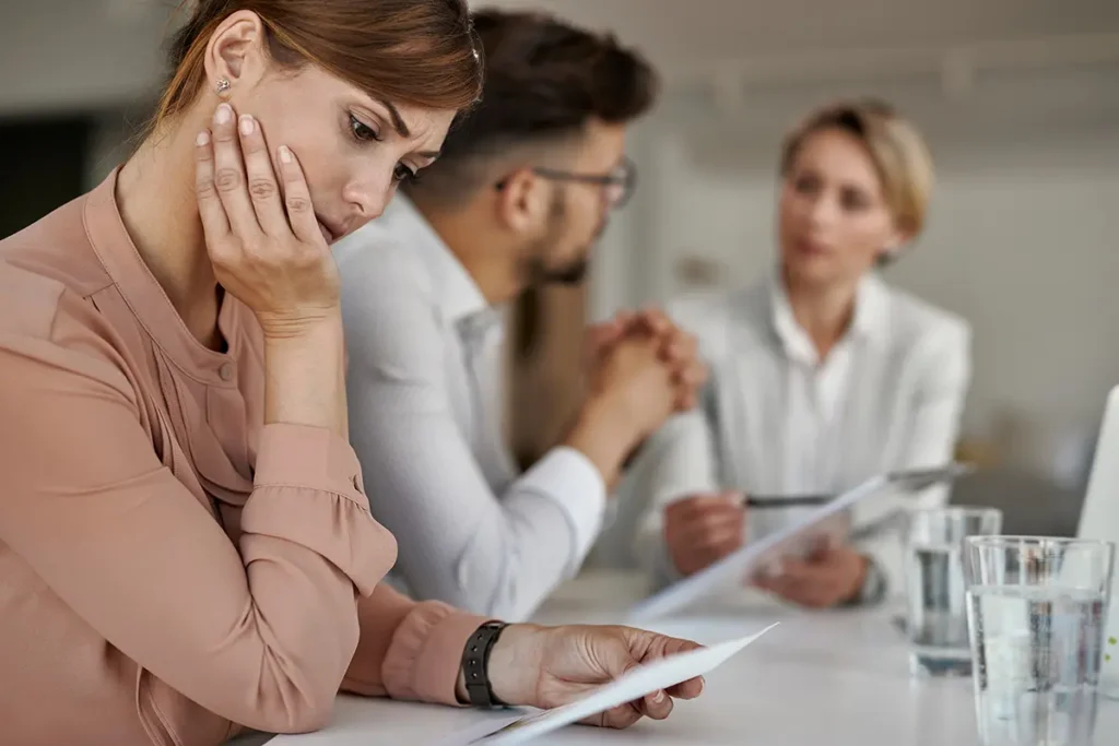 Zestresowana pracowniczka HR analizująca papierowe dokumenty – koszmar manualnego onboardingu bez automatyzacji