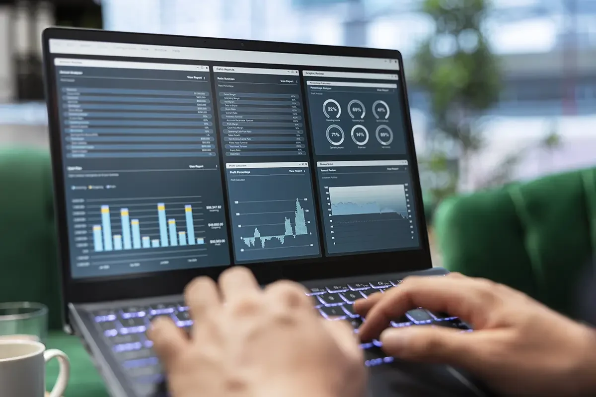 Przedsiębiorca analizujący raporty finansowe i wykresy na laptopie z dashboardem — przykład zastosowania dedykowanej aplikacji zamiast rozwiązania SaaS w małej firmie